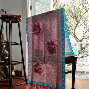 kain batik dengan aksen bunga mawar berwarna merah, diatas batik dengan kombinasi warna pink dan biru yang menjadikan selendang terlihat manis